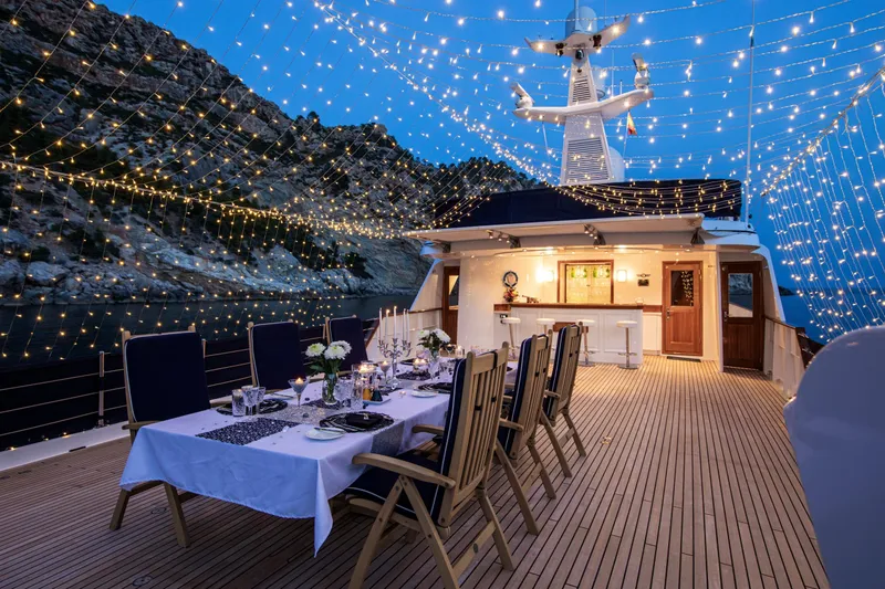 Monaco Yacht Photos Pics Luxurious 1982 Feadship Classic yacht deck with elegant dining setup and twinkling string lights.