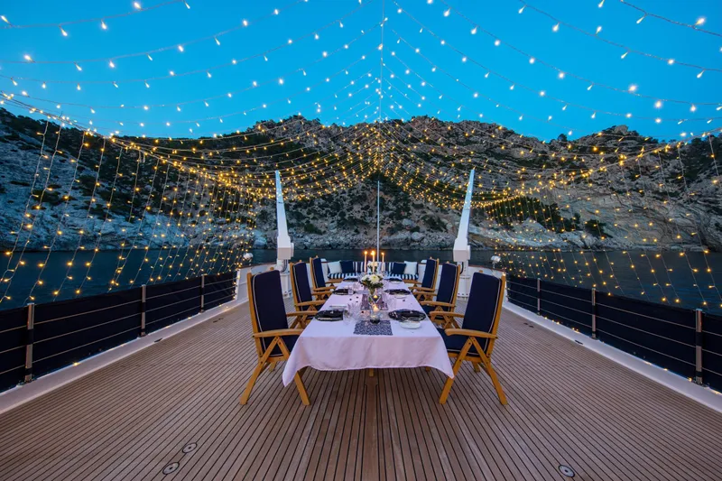 Monaco Yacht Photos Pics Luxurious 1982 Feadship Classic yacht deck with elegant dining setup and twinkling string lights.