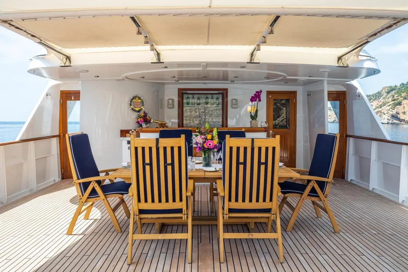 Monaco Yacht Photos Pics Luxurious 1982 Feadship Classic yacht deck with elegant dining setup and ocean view.