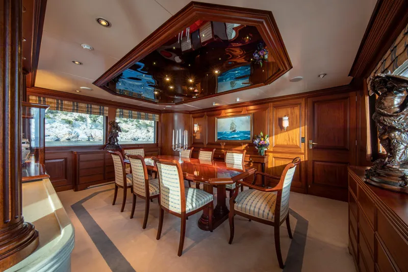 Monaco Yacht Photos Pics Luxurious dining room on 1982 Feadship Classic yacht with elegant wood paneling and plush seating.