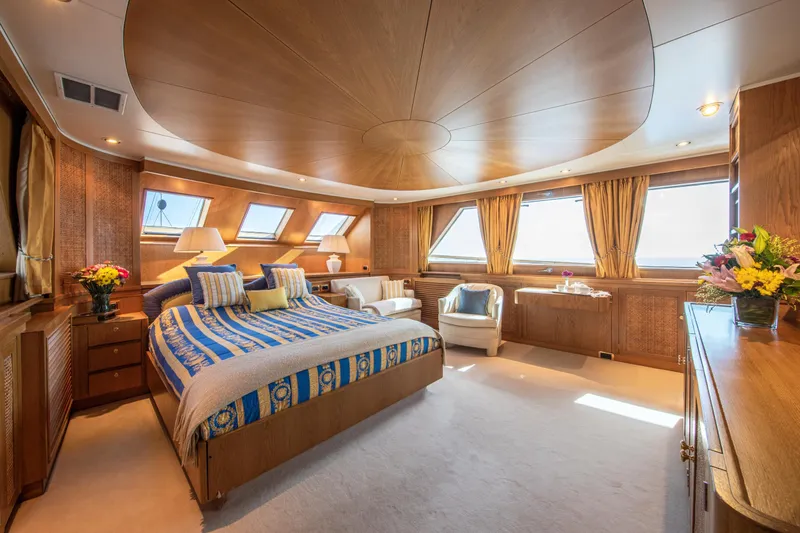 Monaco Yacht Photos Pics Luxurious 1982 Feadship Classic yacht bedroom with elegant wood paneling and large windows.