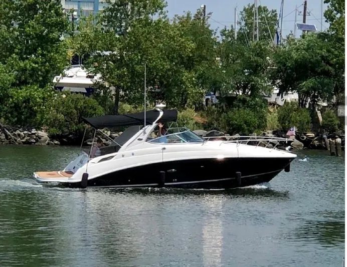  Yacht Photos Pics 2017 Sea Ray Sundancer 280 cruising on a calm river with lush greenery in the background.