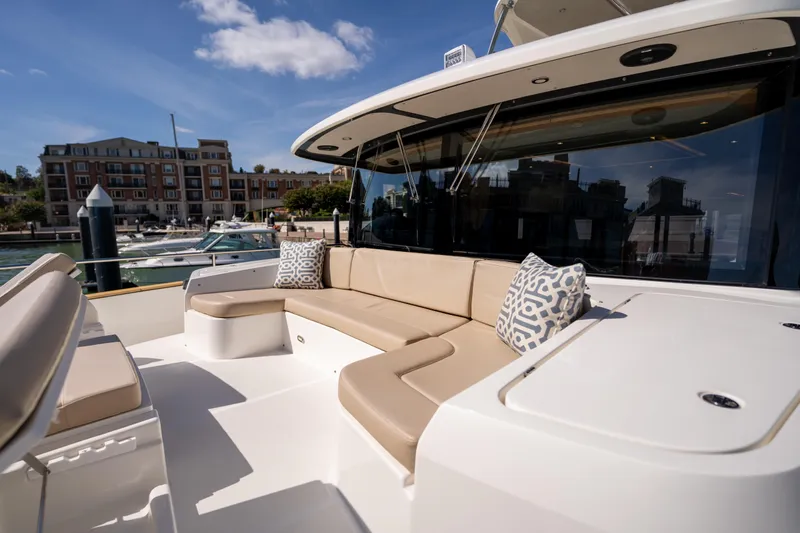 Forever Young Yacht Photos Pics Luxurious seating area on 2018 Absolute 58 Navetta yacht, docked near waterfront buildings.
