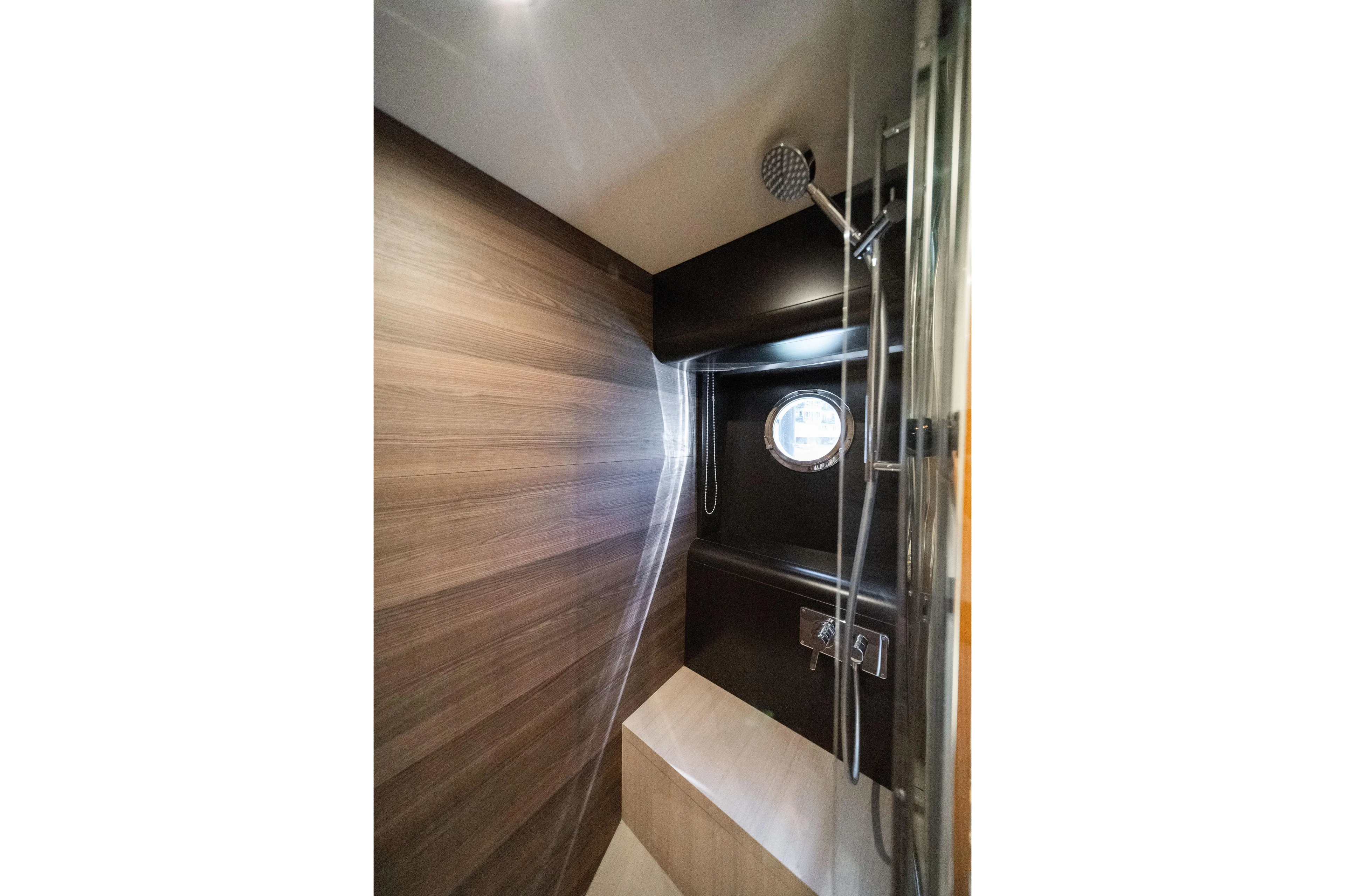 Forever Young Yacht Photos Pics Luxurious shower interior of 2018 Absolute 58 Navetta yacht with wood paneling and porthole.