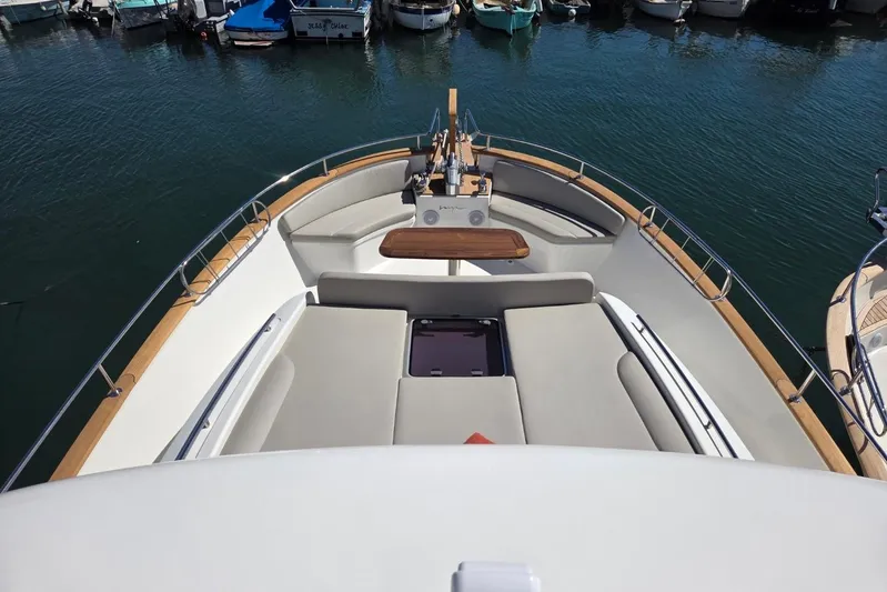  Yacht Photos Pics 2025 Sasga Yachts Menorquin 48 bow with cushioned seating and wooden table in marina.