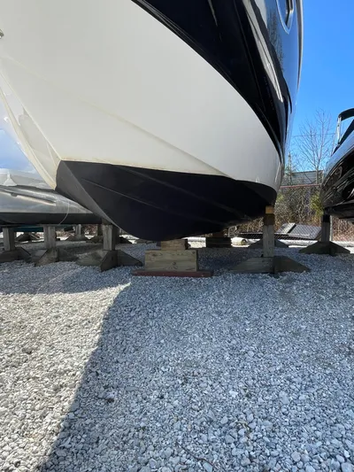 Yacht Photos Pics 2018 Chaparral 310 Signature boat on gravel, supported by wooden blocks.