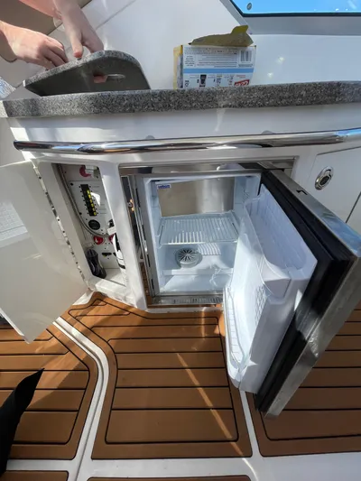  Yacht Photos Pics 2018 Chaparral 310 Signature boat interior with open mini fridge and wooden flooring.