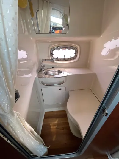  Yacht Photos Pics 2018 Chaparral 310 Signature boat bathroom with sink, mirror, and porthole window.