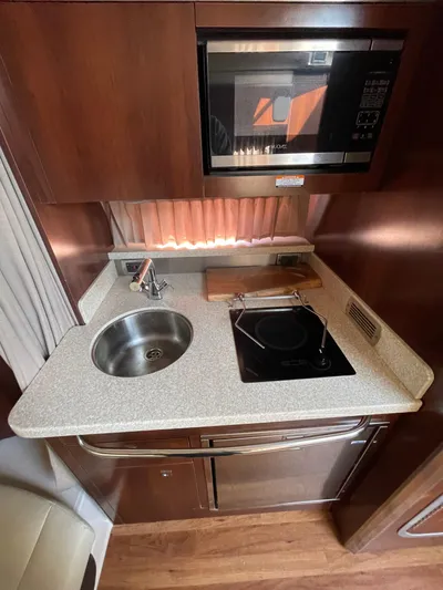  Yacht Photos Pics Compact kitchen in 2018 Chaparral 310 Signature boat with sink, stove, and microwave.