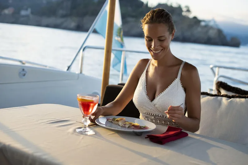 Manu Yacht Photos Pics Woman dining on a 2006 Mangusta 92 yacht, enjoying a meal with a scenic ocean view.