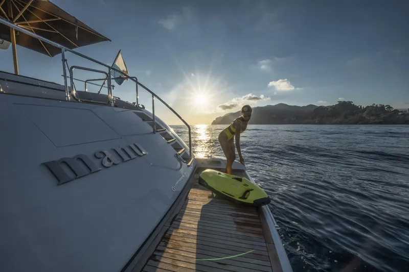 Manu Yacht Photos Pics Luxury Mangusta 92 yacht at sunset, woman with surfboard on deck, 2006 model.