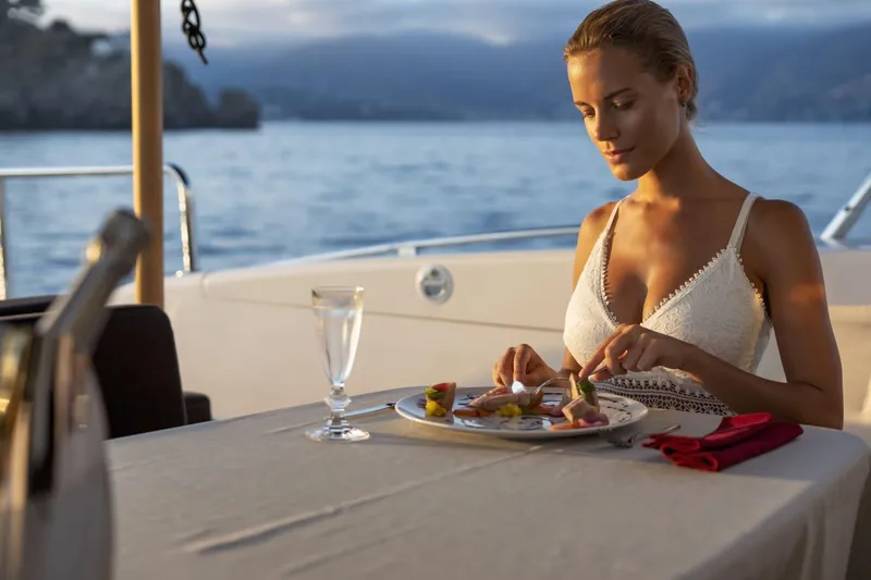 Manu Yacht Photos Pics Woman dining on a 2006 Mangusta 92 yacht, enjoying a meal with a scenic ocean view.