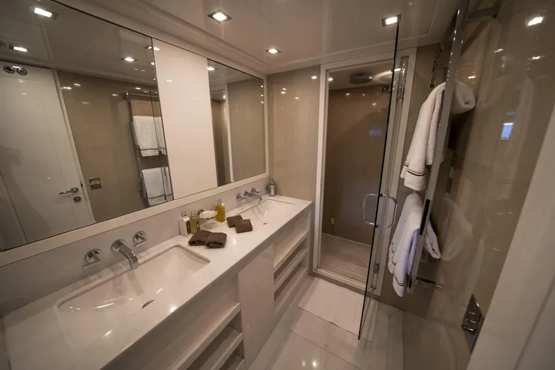 Manu Yacht Photos Pics Luxurious bathroom interior on 2006 Mangusta 92 yacht, featuring double sinks and glass shower.