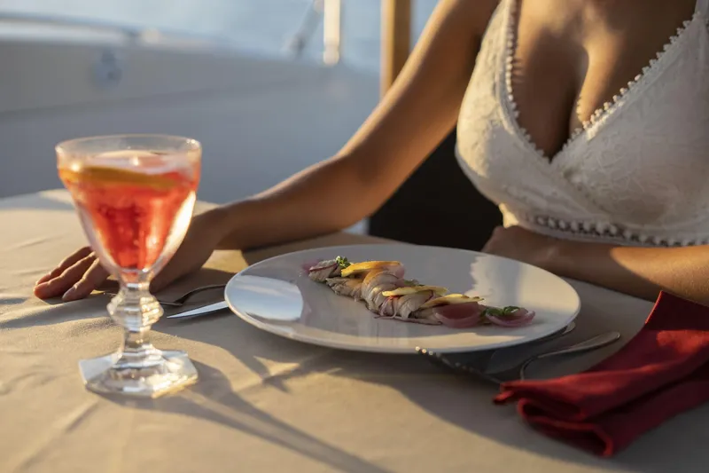 Manu Yacht Photos Pics Elegant dining on a 2006 Mangusta 92 yacht with gourmet dish and cocktail.