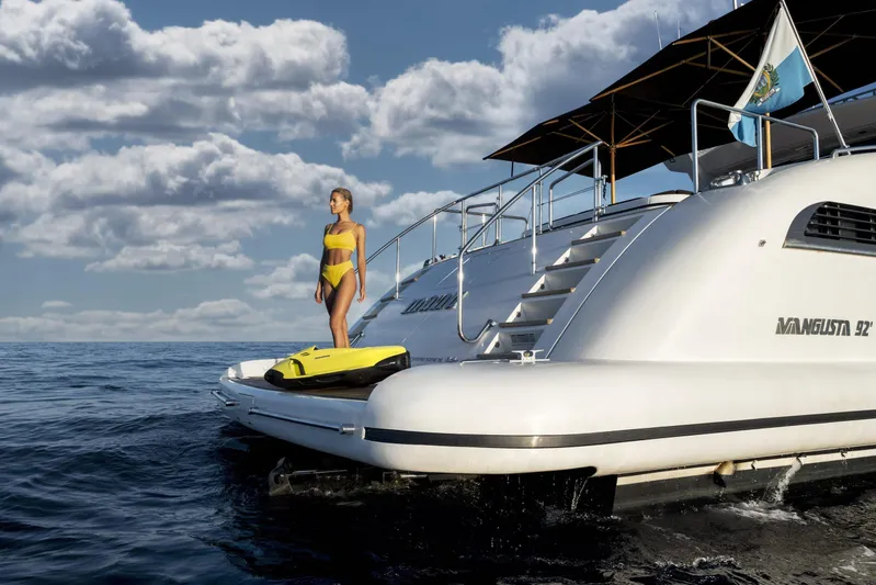 Manu Yacht Photos Pics Woman in yellow bikini on 2006 Mangusta 92 yacht, ocean backdrop, cloudy sky.