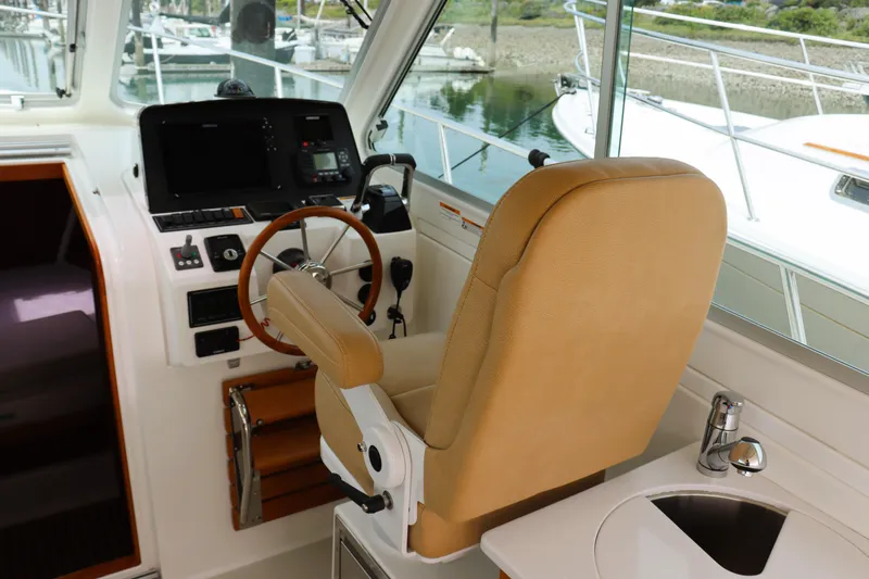 Polo Lounge Yacht Photos Pics 2020 Back Cove 34O helm with tan seat, steering wheel, and navigation controls.
