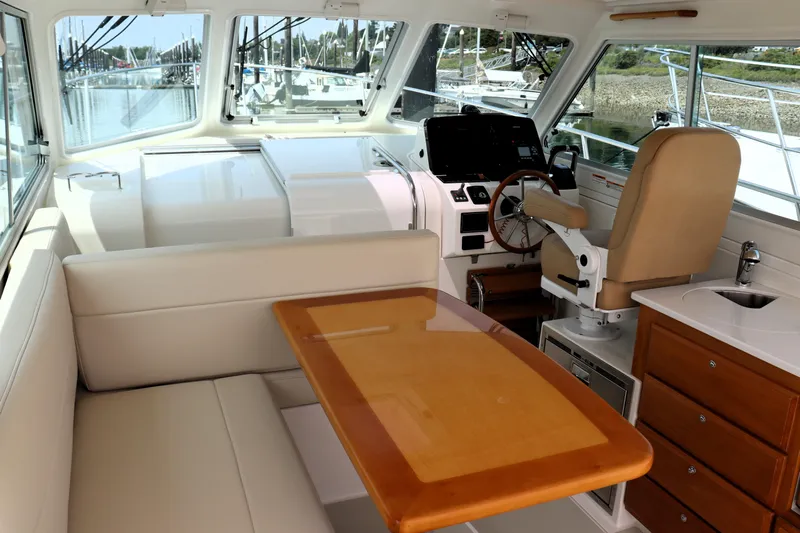 Polo Lounge Yacht Photos Pics Interior of 2020 Back Cove 34O yacht with helm, seating, and wooden table.