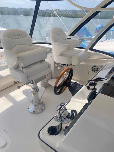  Yacht Photos Pics 2005 Sea Ray Sedan Bridge helm with white captain chairs and wooden steering wheel.