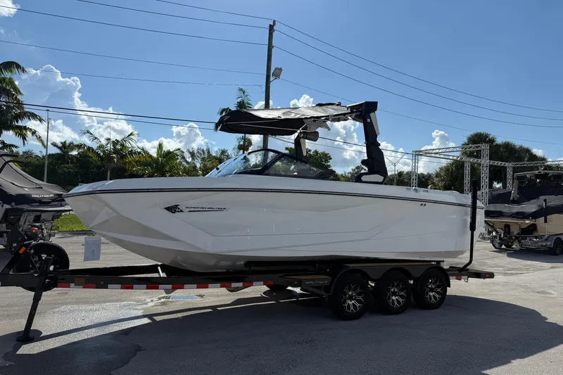  Yacht Photos Pics 2022 Nautique Super Air Nautique G23 boat on trailer, sunny day, palm trees in background.