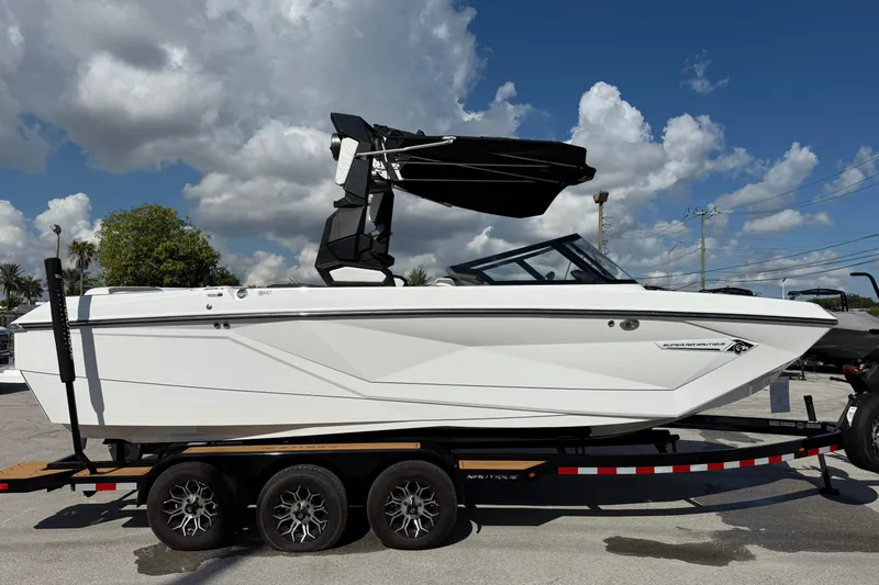  Yacht Photos Pics 2022 Nautique Super Air Nautique G23 boat on trailer under cloudy sky.