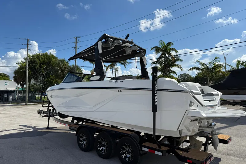  Yacht Photos Pics 2022 Nautique Super Air Nautique G23 boat on trailer, parked outdoors under blue sky.