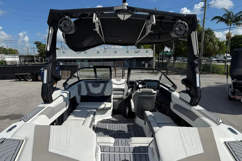  Yacht Photos Pics 2022 Nautique Super Air Nautique G23 boat interior with seating and speakers under a sunny sky.