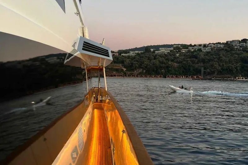  Yacht Photos Pics Heesen 1985 pleasure vessel on serene water at sunset, with distant shoreline view.