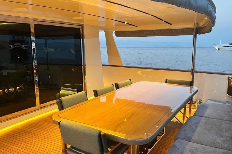  Yacht Photos Pics Luxurious 1985 Heesen Pleasure Vessel with elegant outdoor dining area at sunset.