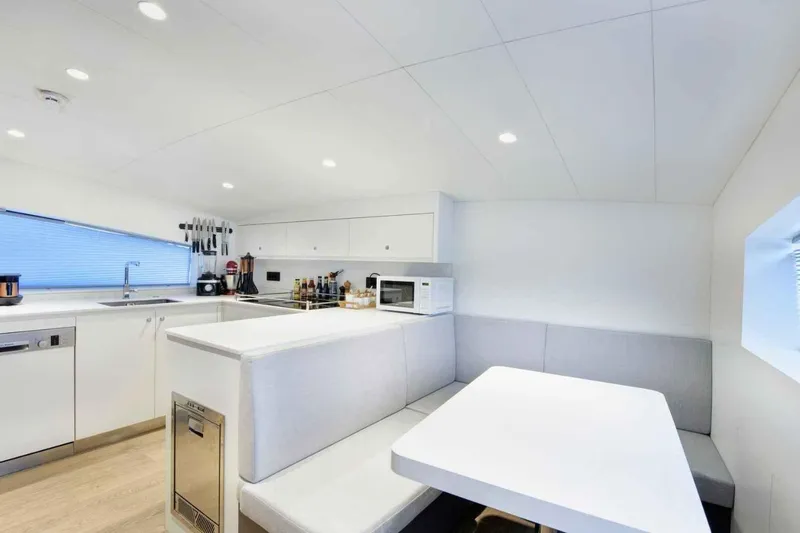  Yacht Photos Pics Modern kitchen interior on 1985 Heesen Pleasure Vessel, featuring sleek white cabinetry and dining area.