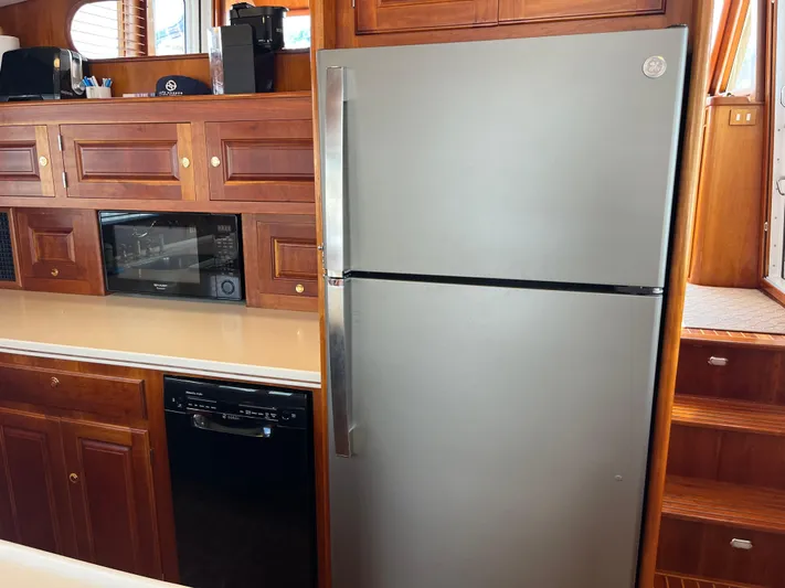 Angus III Yacht Photos Pics Kitchen area in 1998 Alden 56 PHMY yacht with stainless steel fridge and wooden cabinetry.