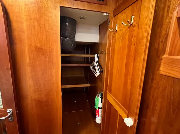 Angus III Yacht Photos Pics Wooden closet interior with shelves, hangers, and a fire extinguisher in a 1998 Alden 56 PHMY.