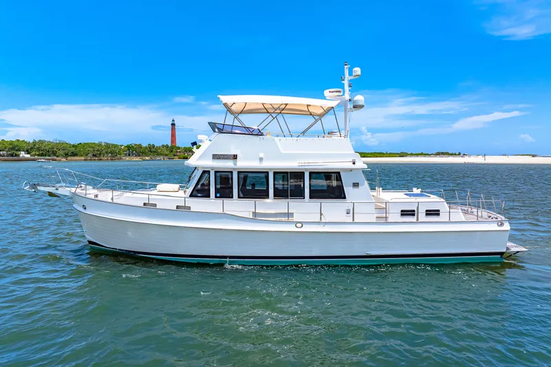 Grazie Yacht Photos Pics 2008 Grand Banks 47 Classic yacht cruising on a sunny day near a lighthouse.