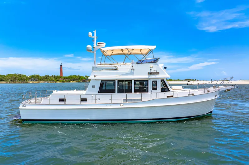 Grazie Yacht Photos Pics 2008 Grand Banks 47 Classic yacht cruising on a sunny day near a lighthouse.