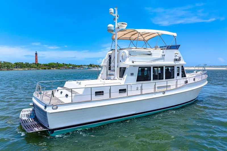 Grazie Yacht Photos Pics 2008 Grand Banks 47 Classic yacht cruising near a lighthouse on a sunny day.