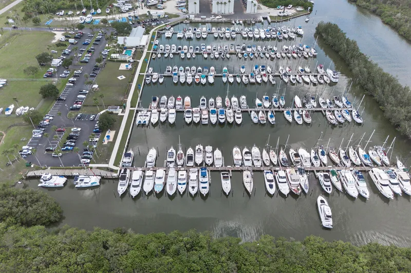 Cocoa Bella Yacht Photos Pics Aerial view of a marina with numerous boats docked, surrounded by lush greenery.