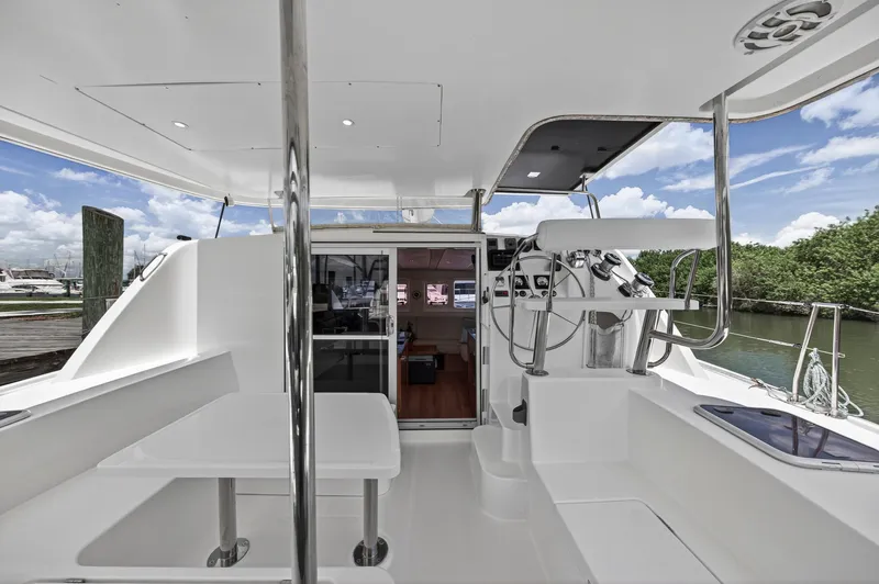 Cocoa Bella Yacht Photos Pics 2011 Leopard 38 catamaran cockpit with helm, seating, and table, docked by lush greenery.