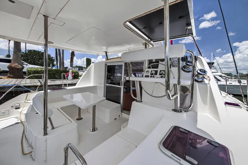 Cocoa Bella Yacht Photos Pics 2011 Leopard 38 yacht cockpit with seating, table, and steering wheel under a clear blue sky.