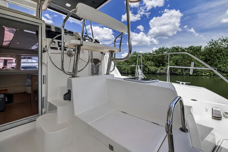 Cocoa Bella Yacht Photos Pics 2011 Leopard 38 yacht cockpit with steering wheel, seating, and lush greenery in the background.