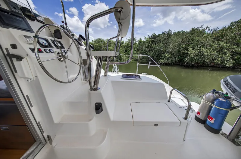 Cocoa Bella Yacht Photos Pics Helm of 2011 Leopard 38 catamaran with steering wheel and controls, docked near lush greenery.
