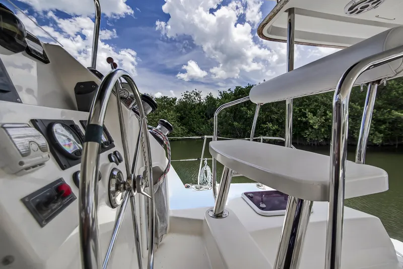 Cocoa Bella Yacht Photos Pics Steering wheel and controls of 2011 Leopard 38 yacht, with lush greenery and cloudy sky.