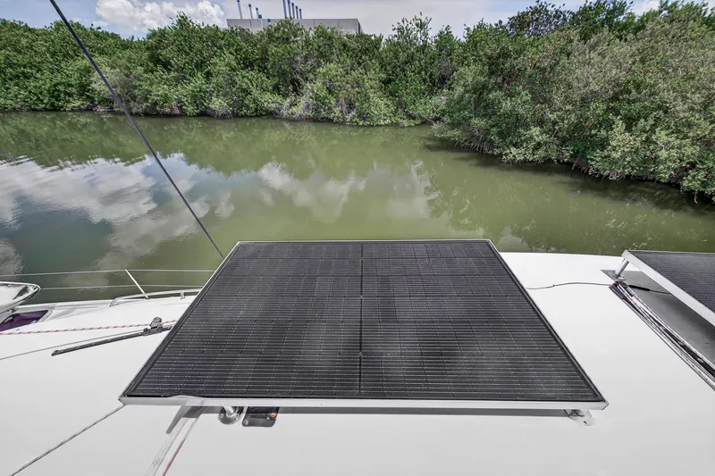 Cocoa Bella Yacht Photos Pics Solar panels on a 2011 Leopard 38 catamaran, docked by lush greenery and calm water.