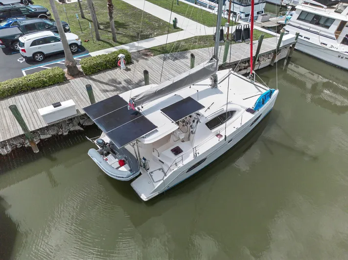 Cocoa Bella Yacht Photos Pics Aerial view of a 2011 Leopard 38 catamaran docked, featuring solar panels and a dinghy.