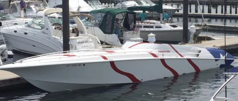  Yacht Photos Pics 1998 Fountain 42 Lightning speedboat docked, featuring sleek design and red stripes.