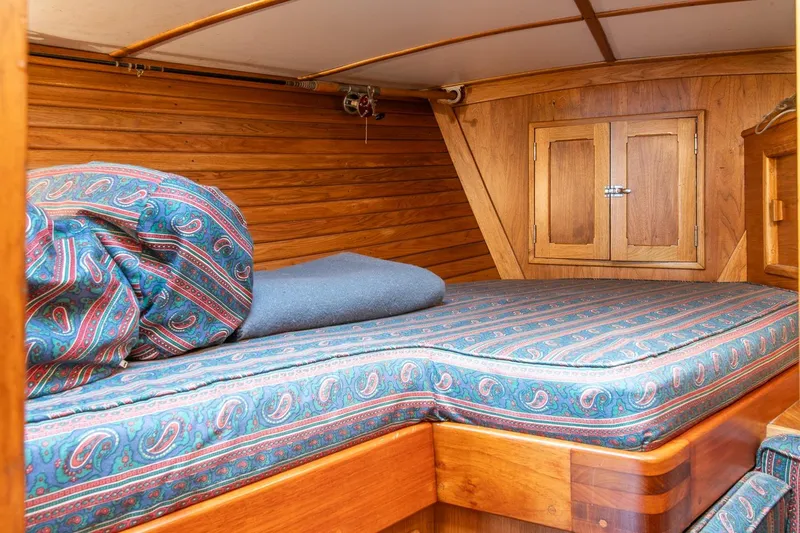Aleyah Yacht Photos Pics Cozy cabin interior of 1984 Hank Hinckley OC42 sailboat with patterned bedding and wooden walls.