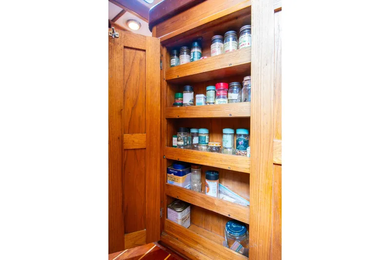 Aleyah Yacht Photos Pics Wooden spice cabinet on 1984 Hank Hinckley OC42 boat, filled with various jars and containers.