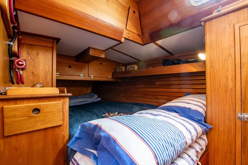 Aleyah Yacht Photos Pics Cozy cabin interior of 1984 Hank Hinckley OC42 sailboat with wooden furnishings and striped bedding.