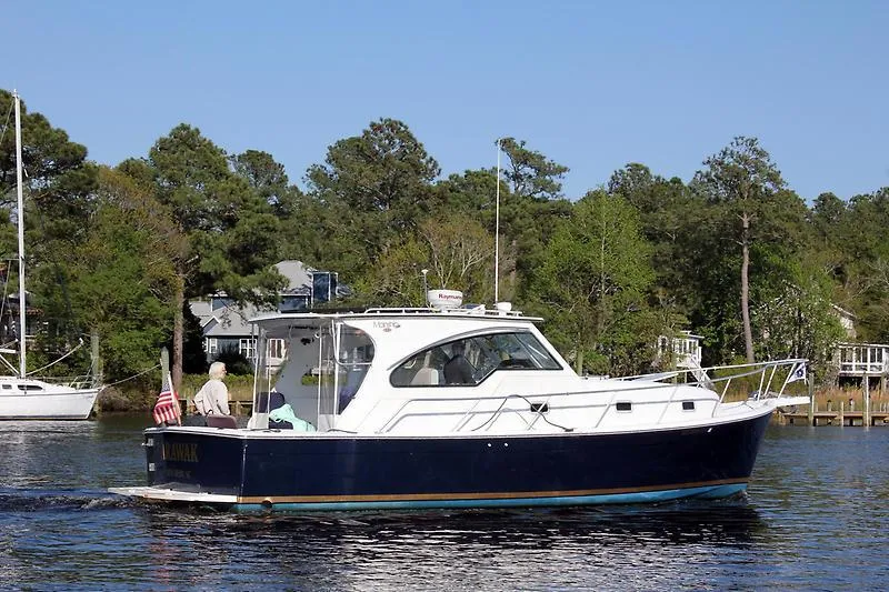 Aweigh Yacht Photos Pics 2001 Mainship Pilot 34 Sedan cruising on a calm river with trees in the background.