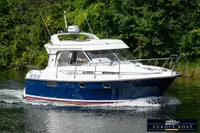 Nimbus 310 Coupe 2000 cruising on a serene waterway with lush greenery.