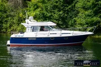 Nimbus 310 Coupe 2000 boat cruising on a calm river with lush green background.