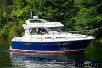 Nimbus 310 Coupe 2000 boat cruising on a serene waterway, surrounded by lush greenery.